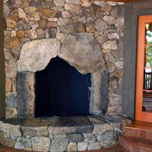 Mosaic style New England fieldstone fireplace & hearth with large weathered stones surrounding firebox