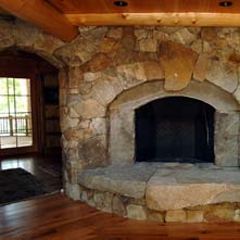Double arched granite and fieldstone fireplace with large weathered stone hearth