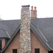 Fieldstone chimney with copper cap on an English Tudor style home