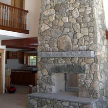 Pass-through fieldstone fireplace with antique granite lintel and Swenson gray granite mantel & hearth